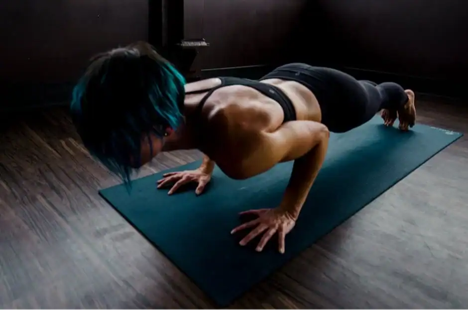 A fit woman Targeting Specific Muscle Groups performs a push-up on a yoga mat indoors, showcasing strength and focus.